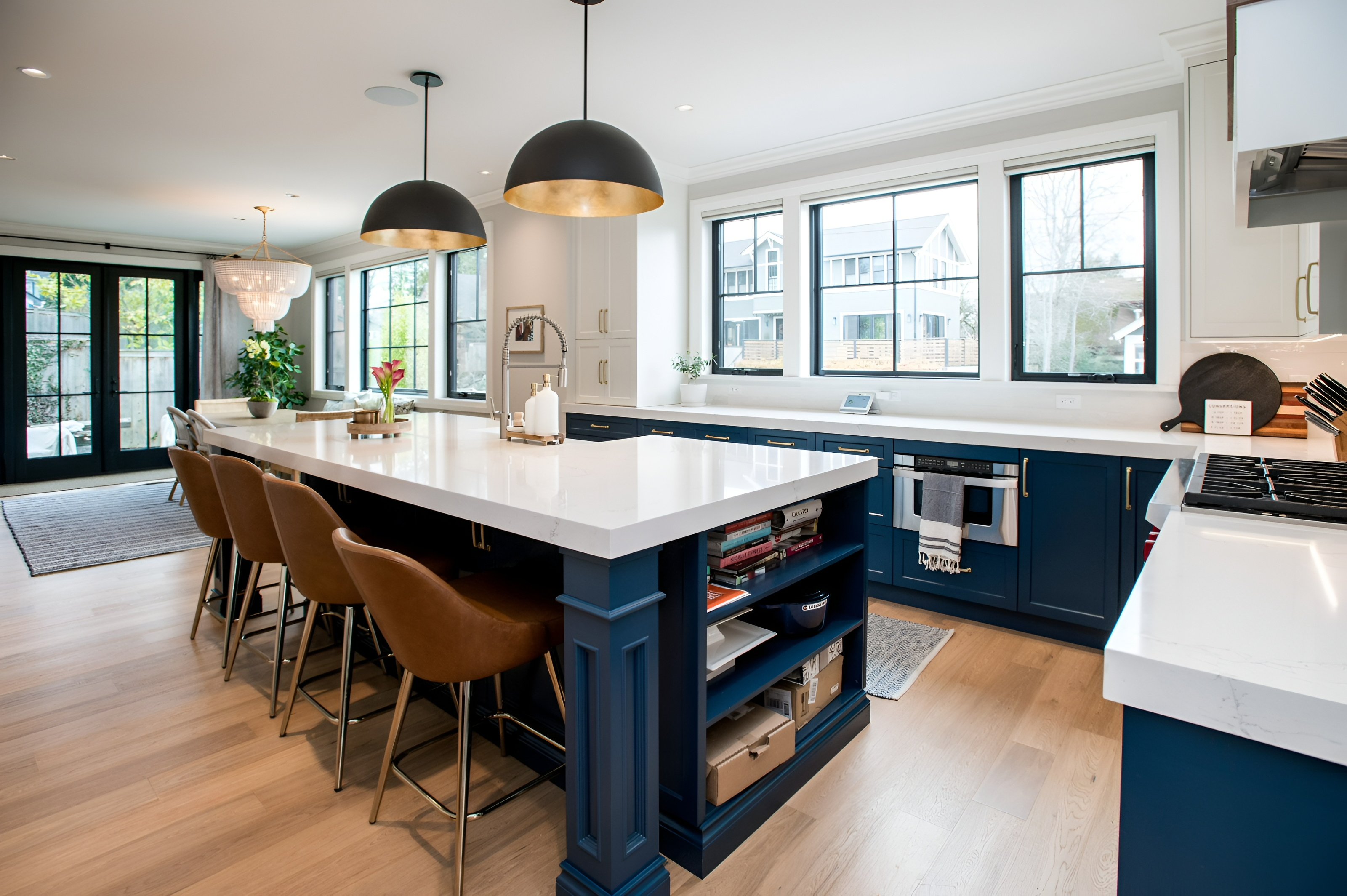 Navy blue shaker kitchen with white quartz waterfall island and brass-lined dome pendants